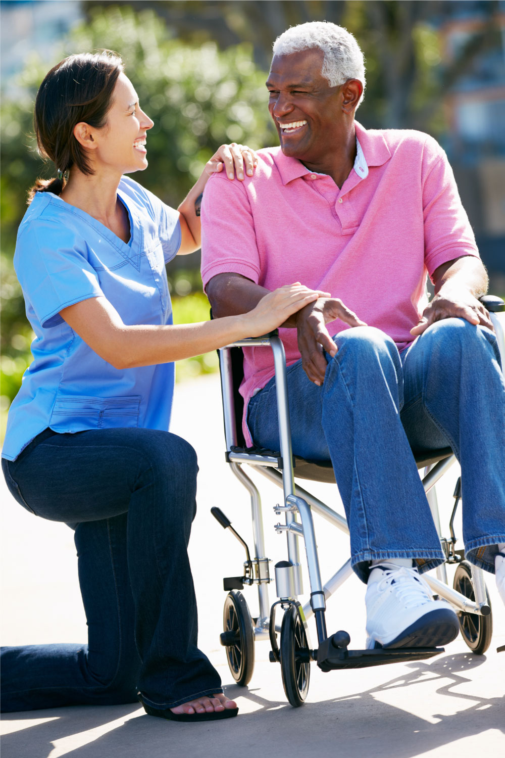 a female carer with a man in a wheelchair, both are smiling